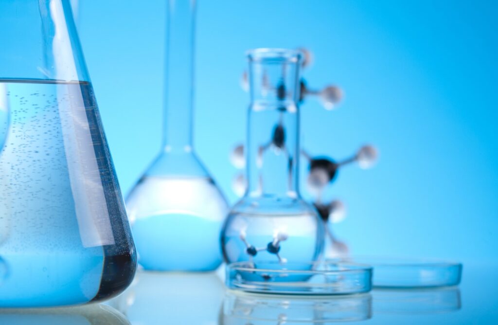 Test tubes, beakers, and a model of an element on a table.
